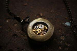 Close-up of a vintage gold pocket watch with visible gears on a wooden background.