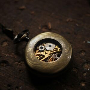 Close-up of a vintage gold pocket watch with visible gears on a wooden background.